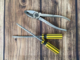 Steel pliers and screwdrivers on a wooden table