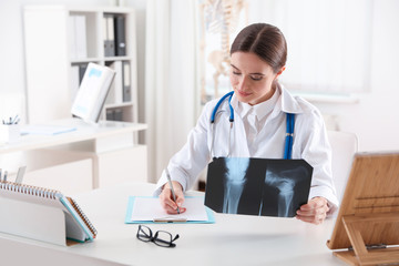 Sticker - Orthopedist examining X-ray picture at desk in clinic