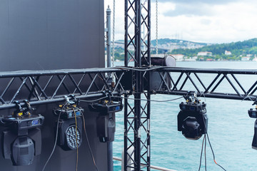 Installation of professional sound, light, video and stage equipment for a concert. Stage lighting equipment is clamped on a truss for lifting. Flight cases with cables..