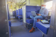 © Panumas - Hipster man with face mask sitting and traveling by train working on laptop in new normal style. New normal business travel concept.
