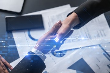 Double exposure of two businesspeople handshake and binary technology hologram drawing background. Concept of partnership and agreement. Formal wear.