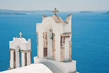 Two bell towers of Oia, Santorini, Greece with caldera at the background