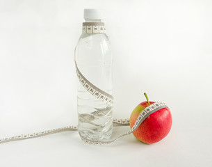 apple with tape measure, measuring tape isolated on white background. Apple and transparent bottle of water isolated on white background - diet concept