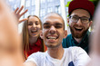 Selfie time. Group of friends taking a stroll on city's street in summer day. Handicapped man with his friends having fun. Inclusion and diversity concept, normal lifestyle of special groups of