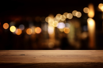 Wall Mural - background Image of wooden table in front of abstract blurred restaurant lights