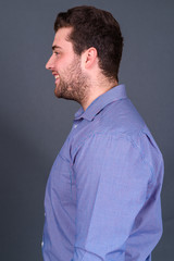 Portrait of happy young handsome overweight bearded businessman