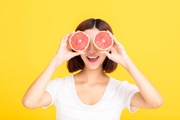 Wall Mural - Young beautiful woman showing orange on yellow background