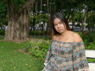 Portrait of young overweight Asian woman at the park