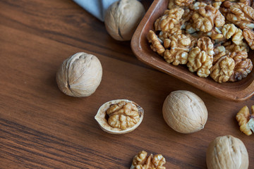 Walnuts kernels on dark desk with color background, Whole walnut in wood vintage bowl.