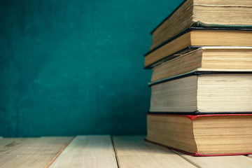 Poster - Old books on a old wooden table. Beautiful green wall background.