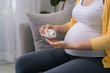 © makistock - Pregnant woman holding plastic jar with pills, taking vitamins and minerals