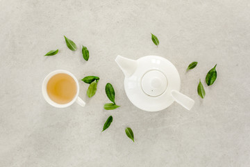 Wall Mural - Herbal tea with two white tea cups and teapot, with green tea leaves. Flat lay, top view. Tea concept