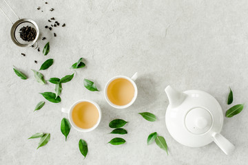 Wall Mural - Herbal tea with two white tea cups and teapot, with green tea leaves. Flat lay, top view. Tea concept