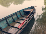 Fototapeta Na sufit - Old wooden boat with red paddle in the water on the river, summer day