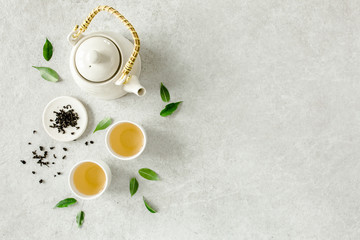 Wall Mural - Herbal tea with two white tea cups and teapot, with green tea leaves. Flat lay, top view. Tea concept