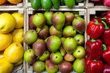 Pears oranges and sweet red peppers in boxes.