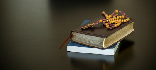 Holy bible book and wooden cross on black desk in church,prepare to study bible in christian religion-panoramic banner for web header