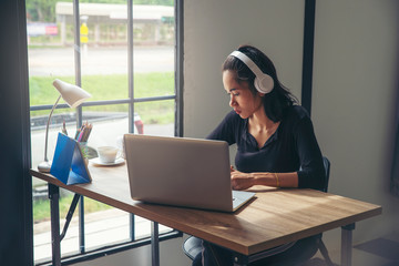 Wall Mural - Businesswoman working online at the home office via laptop. Asian young entrepreneur watching webinars and talking during meeting video conference calls with team. 