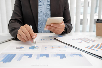 The hands of a male businesswoman are analyzing and calculating the annual income and expenses in a financial graph that shows results To summarize balances overall in office