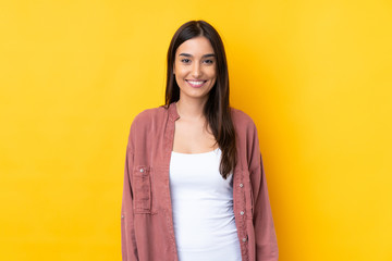 Wall Mural - Young brunette woman over isolated yellow background laughing