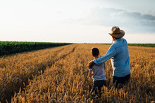 Man Holding His Grandson Standing In Wheat Field