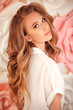 Beauty Makeup. Red hair girl model with long wavy hairstyle and shiny eyeshadows. Portrait of young attractive caucasian woman posing over flowers wall.