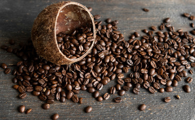 Roasted arabica coffee beans scattered on a wooden table from a coconut. Fresh coffee beans.