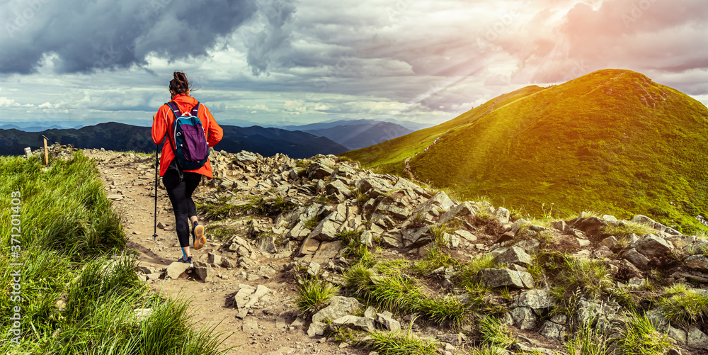 Girl hiking in mountains at sunset. Hiking trail in Bieszczady Poland. Lonley hiker in the mountains. Woman conquer mountains. - obrazy, fototapety, plakaty 