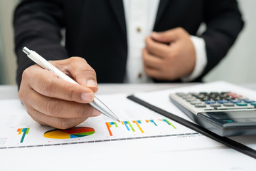 Asian accountant working and analyzing financial reports project accounting with chart graph and calculator in modern office,finance and business concept.