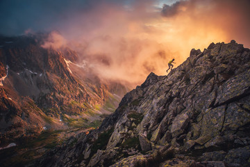 Wall Mural - Silhouette of active hiker running in mountains. Orange landscape in background. Edit space, sport photo hilly landscape..