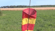 Red And Yellow Windsock Wind Sock On Blue Sky On The Aerodrome, Yellow Field And Clouds Background
