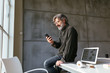 © Bonninstudio/Stocksy - Senior employee using smartphone in office