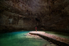 Woman Standing In The Middle Of A Lake In A Cave