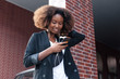 © Viktor Solomin/Stocksy - Beautiful black african american business woman are walking on the street with smartphone