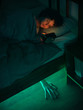 © Duet Postscriptum/Stocksy - Helloween story. The girl uses a smartphone in bed, and a mystical light shines under the bed.