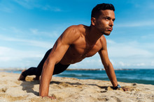 Young Hispanic Man Doing Push Ups On The Beach Without T-shirt . Ripped And Lean Sporty Body