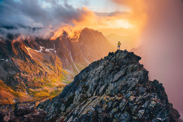 Man on the top of the hill watching wonderful scenery in mountains during summer colorful sunset in High Tatras in Slovakia..