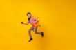 active schoolboy with a backpack, books and an Apple runs on a yellow background