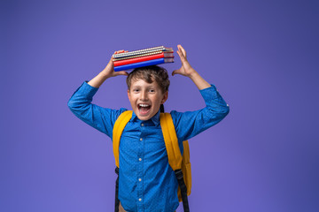 Back to school! A cheerful schoolboy against a purple paper wall.