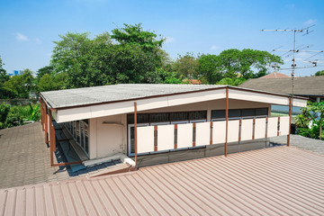 second floor house building with pattern tiles roof. brown metal sheet roofs.