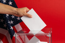 Man Putting Ballot Into Voting Box On Red Background With American Flag