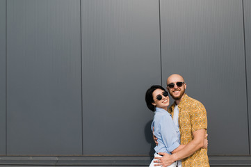 Caucasian couple in love. Young and happy loving couple dressed in stylish casual wear and sunglasses spend time together they hugging and smiling