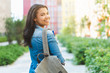 © wpadington - Attractive smiling dark skinned student girl posing outdoors looking back over her shoulder