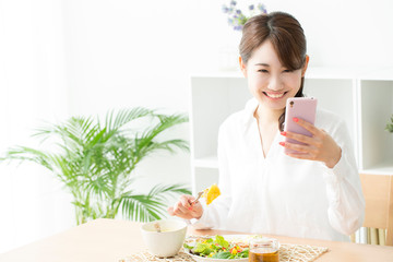 Canvas Print - 食事をしながらスマホを見る女性