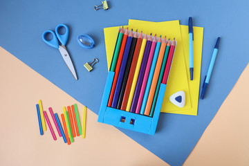 Counting sticks and colored pencils with school supplies on a blue background, top view, close-up