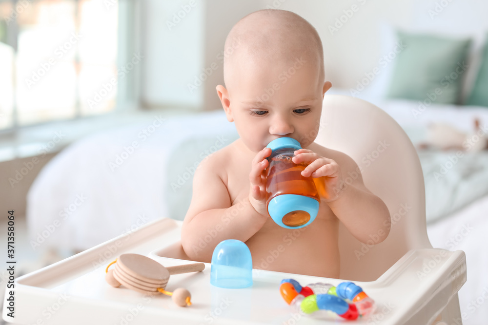 Cute little baby drinking juice from bottle at home