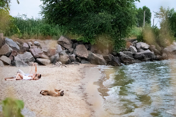 A couple of lovers lies on the beach next to their dog. Camping with pets. Love concept for each other and animals