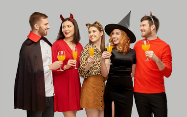 Poster - friendship, holiday and celebration concept - group of happy smiling friends in halloween costumes of vampire, devil, witch and leopard toasting drinks over grey background