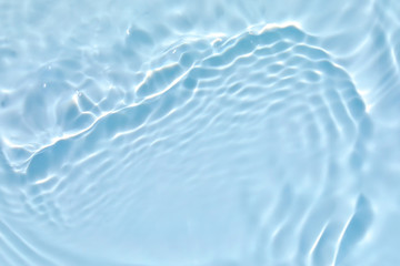 Blurred transparent blue colored clear calm water surface texture with splashes and bubbles. Trendy abstract nature background. Water waves in sunlight with copy space.