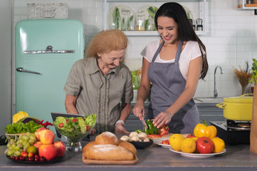 Happy daughter and mother cooks a organic homemade meal in a family kitchen together with smile